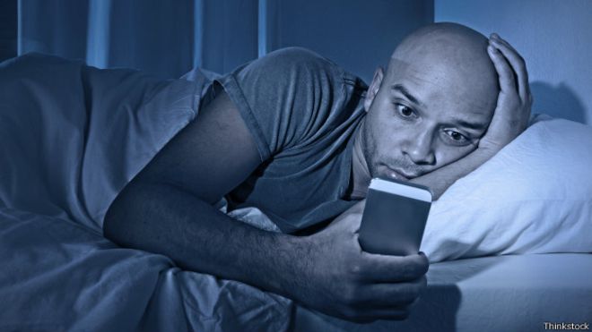 Homem usando celular na cama 