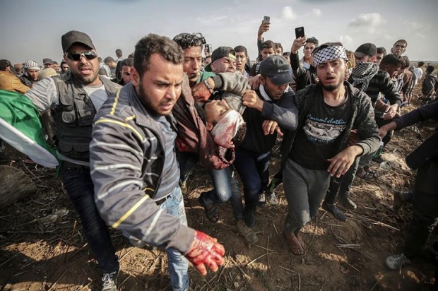 Palestinos ajudam jovem companheiro que morreu durante os enfrentamentos com as tropas do Exército israelense na Faixa de Gaza (Mohammed Saber/Agência EFE/direitos reservados)