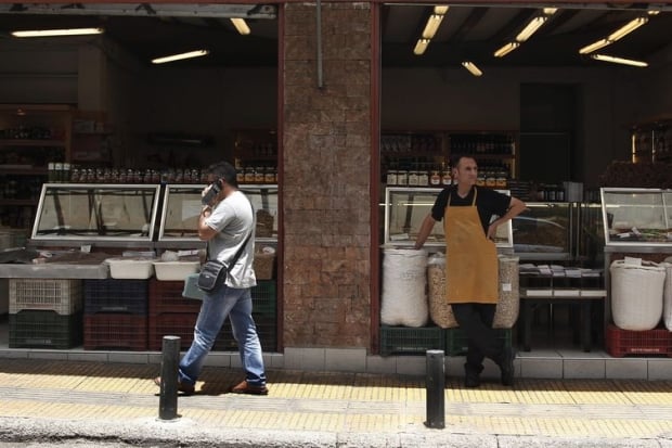 Donos de lojas no centro de Atenas aguardam por clientes, enquanto o país enfrenta severa crise econômica