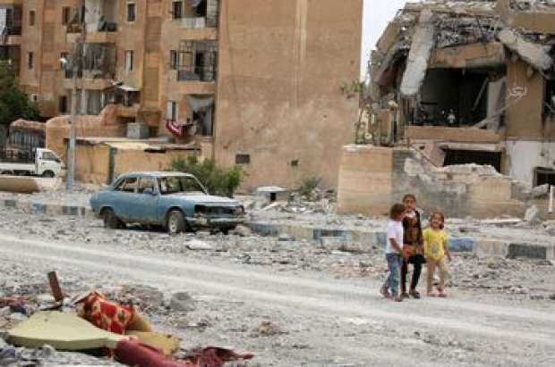 Crianças sírias passeiam entre prédios danificados e ruas cheias de ruínas