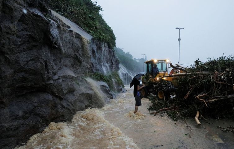 Um homem caminha na avenida Niemeyer durante as fortes chuvas perto da praia de São Conrado no Rio de Janeiro