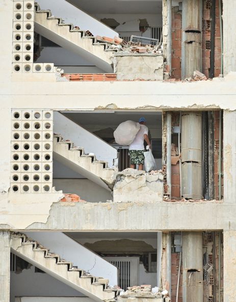 A man carrying belongings walks in a damaged building, after earthquakes hit the country, in La Guaira, Venezuela, June 28, 2026. REUTERS/Maxwell Briceno     TPX IMAGES OF THE DAY
