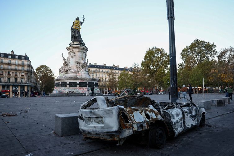 REUTERS/Abdul Saboor/Proibida reprodução A destroyed car near the Marianne statue at the Place de la Republique, with a yellow vest put on it, the day after clashes during a national day of demonstrations against the cost of living and rising fuel prices, in Paris, France, October 18, 2026. The back of the vest reads: 'In 1961 the police drowns Algerian women'. REUTERS/Abdul Saboor TPX IMAGES OF THE DAY