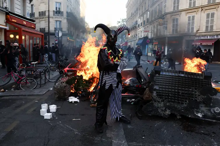 REUTERS/Abdul Saboor/Proibida reprodução A demonstrator wearing a costume stands in front of burning flames, in Paris, France, October 18, 2026. REUTERS/Abdul Saboor